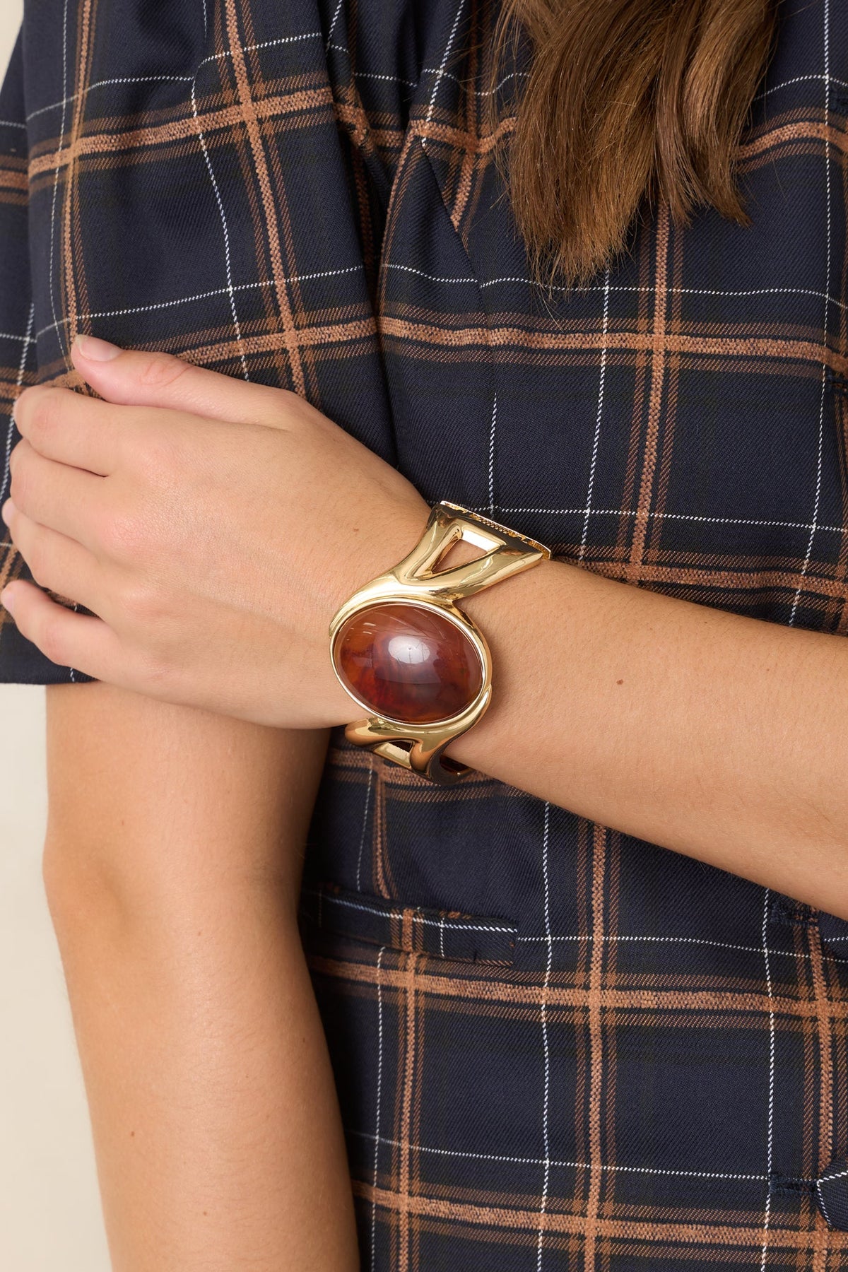 Brazalete rígido con bisagra y pieza central dorada y de ámbar
