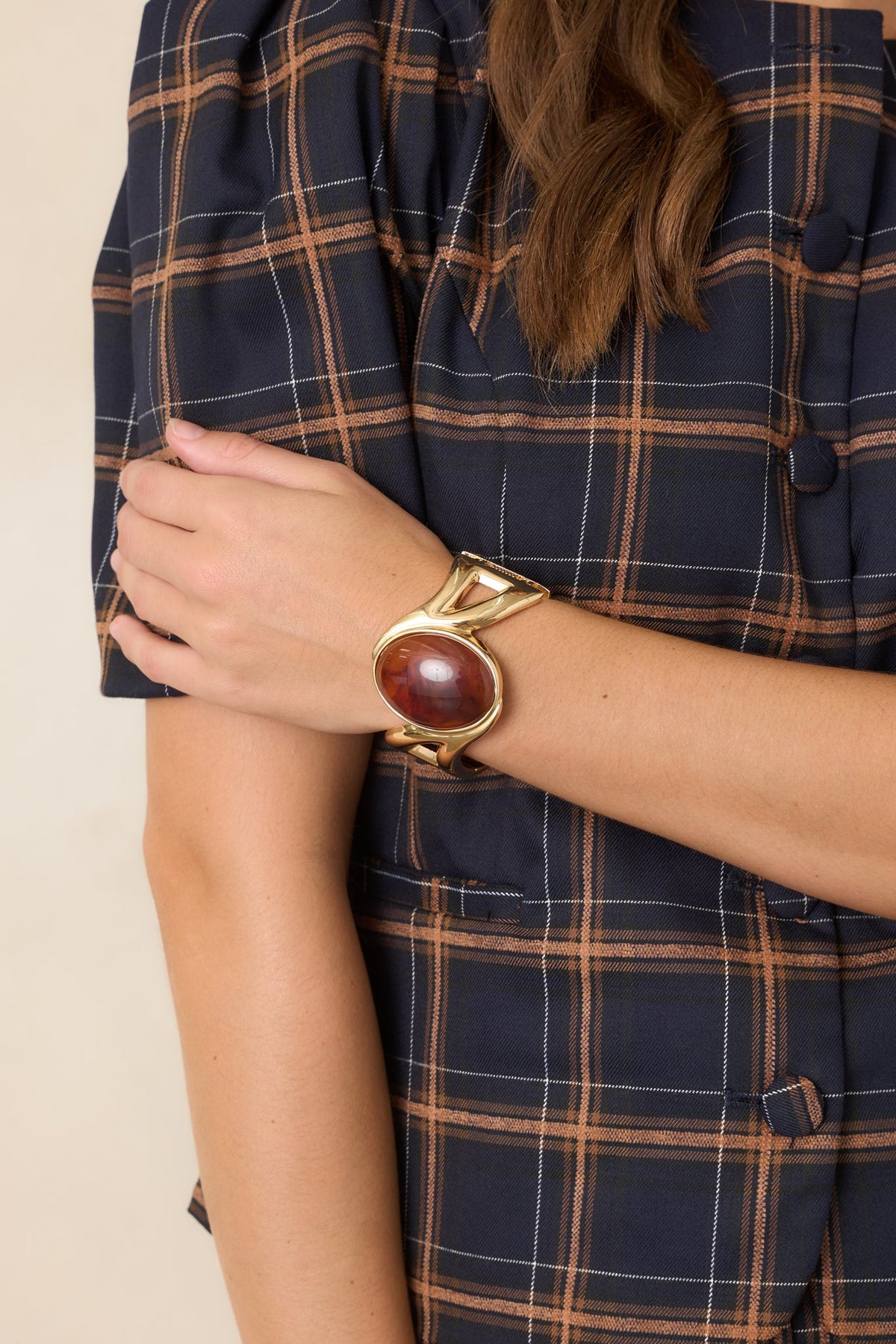 Brazalete rígido con bisagra y pieza central dorada y de ámbar